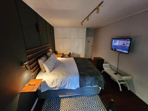 1 dormitorio con 1 cama y TV en la pared en Durbanville Pool House, en Durbanville