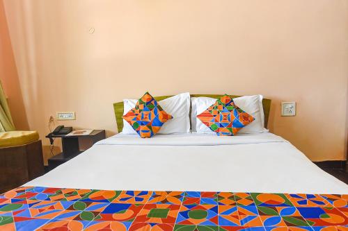Una cama con sábanas y almohadas coloridas. en FabEscape Aqualura Verem With Swimming Pool en Nerul
