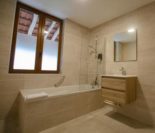 W łazience znajduje się wanna, umywalka i lustro. w obiekcie Le gite du chateau 1 