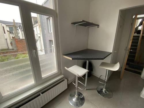 a kitchen with a counter and two stools in front of a window at Antwerp City apartment 3 in Antwerp