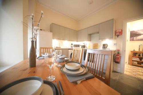a dining room table with plates and wine glasses on it at lfracombe Holiday Apartment Close to Tunnels Beaches in Ilfracombe