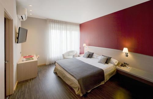a hotel room with a bed and a red wall at Hotel Asturias in Gijón
