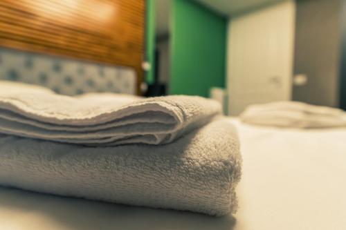 einen Stapel Handtücher auf dem Bett in der Unterkunft Be Your Home - Tower Beach Suite in Civitavecchia