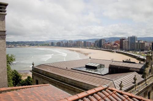a view of a beach with buildings and the ocean at Hotel Asturias in Gijón