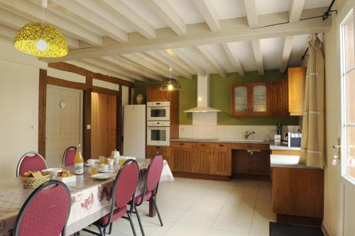 eine Küche mit einem Tisch mit rosa Stühlen und eine Küche mit in der Unterkunft Le pre des marguerites in Rosnay-lʼHôpital