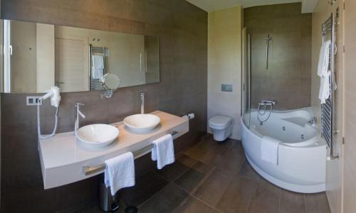 a bathroom with two sinks and a tub and a toilet at Hotel Asturias in Gijón