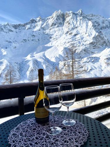 una bottiglia di vino e due bicchieri di vino su un tavolo di Ski paradise - Cielo alto Cervinia a Breuil-Cervinia