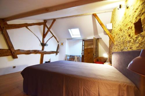 1 dormitorio con 1 cama en una habitación con vigas de madera en Maison de village proche Dordogne, en Lacapelle-Biron