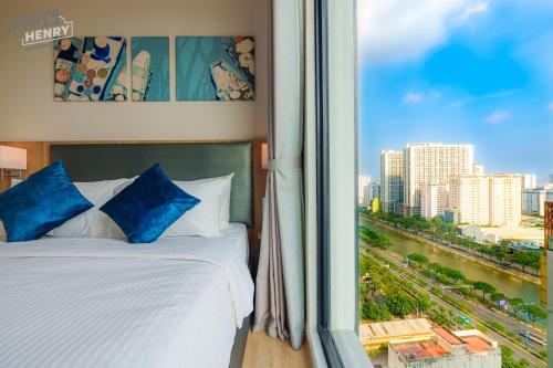 a bed with blue pillows in a room with a window at Son&Henry Zenity District 1 in Ho Chi Minh City