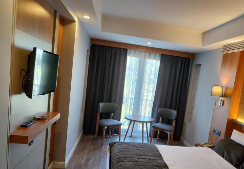 a hotel room with a bed and a tv and a table at May park HOTEL in Izmir
