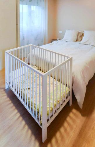 a white crib in a bedroom with a bed at AG Casa Rural Carballo, jardín y playa a 14km in Artes