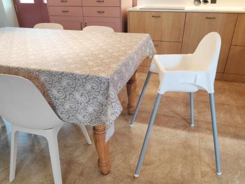 a kitchen with a table and two white chairs at AG Casa Rural Carballo, jardín y playa a 14km in Artes