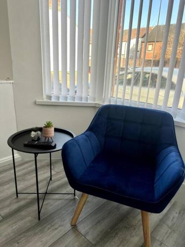 a blue chair and a table in a room with a window at No. 51 - Modern 4 bed in Liverpool