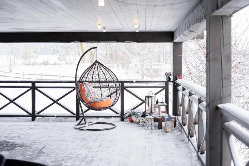 a swing sitting on a porch in the snow at Holiday House "Brūklenes" in Talsi