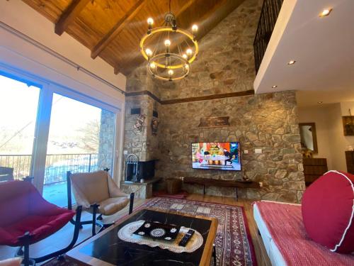 a living room with a stone wall and a chandelier at Villa Gjelbër 1 in Prizren