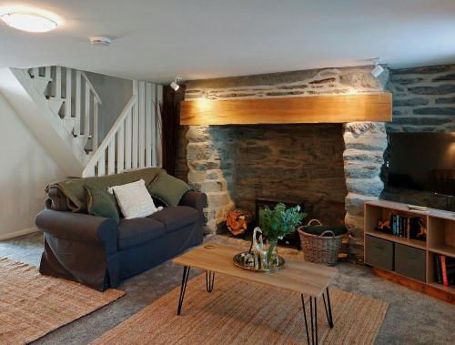 a living room with a couch and a stone fireplace at Craig View Fishermans Cottage nr Harbour and Beach in Barmouth