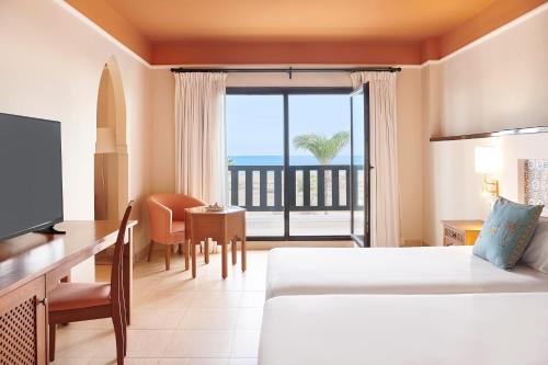 a hotel room with a bed and a desk and a window at Iberostar Waves Saidia in Saidia 
