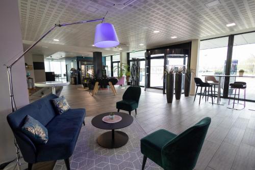 a lobby with a blue couch and chairs and a piano at Campanile Belfort Montbéliard - Gare La Jonxion. in Meroux