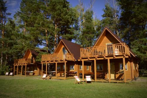 une grande cabane en rondins avec deux terrasses et des chaises dans l'établissement Camping Szczecinek Domy Wypoczynkowe, à Szczecinek