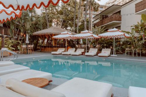 een zwembad met ligstoelen en parasols bij White Sands Hotel in Honolulu