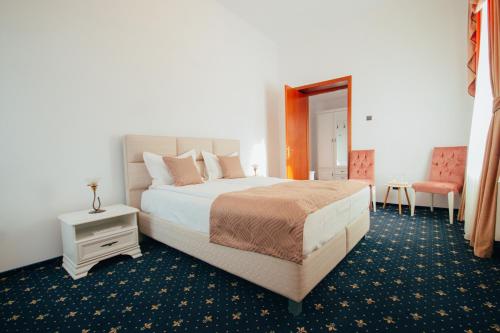ヴァトラ・ドルネイにあるHotel Carol - Vatra Dorneiのベッドルーム1室(ベッド1台、テーブル、椅子付)
