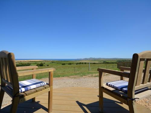 two chairs sitting on a deck with a view of a field at 1 Bed in St Davids 62569 in Abercastle