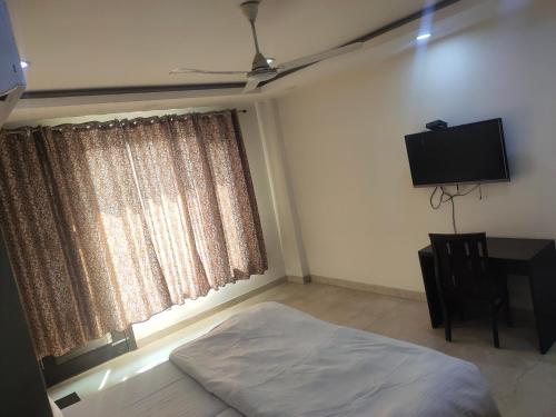 a bedroom with a bed and a desk and a television at A J RESIDENCE in New Delhi