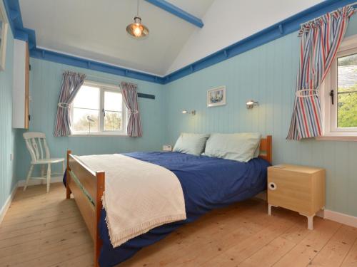 a blue bedroom with a bed and a chair at 1 bed in Llansteffan 74267 in Ferryside