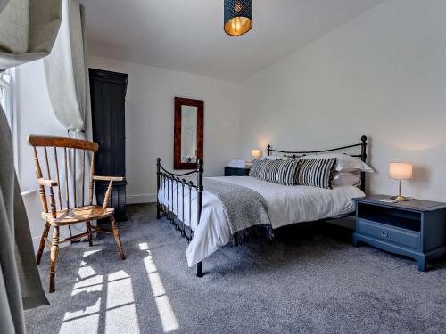 a bedroom with a bed and a chair and a mirror at 2 Bed in Bude 75046 in Kilkhampton