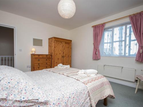 a bedroom with a bed and a dresser and a window at 3 Bed in Studland DC072 in Studland