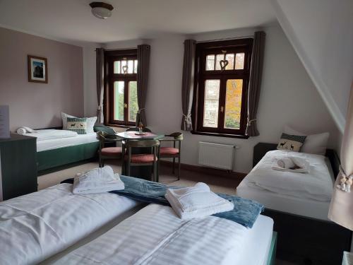 a room with three beds and a table and windows at Auersberg Haus in Eibenstock