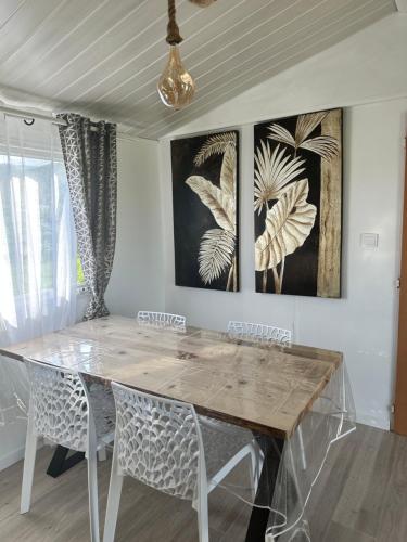mesa de comedor con sillas y pinturas en la pared en les bungalows de Lisa Maria, en SERRA DI FIUMORBO