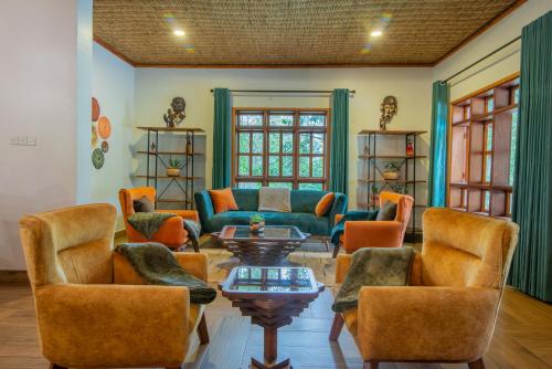 a living room with couches and a table and chairs at Gorilla Leisure Lodge in Kisoro