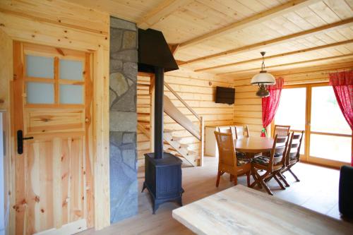 uma sala de jantar com um fogão a lenha num chalé de madeira em Niedźwiedziówka em Jaworki