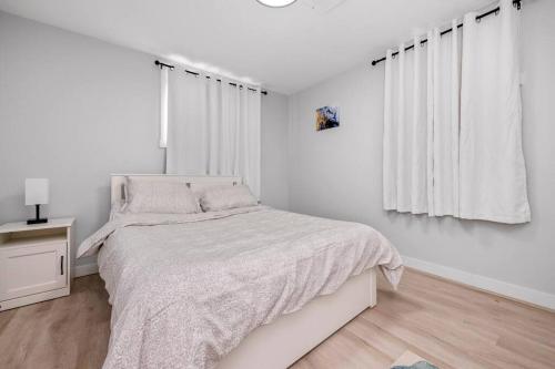 a white bedroom with a bed and a window at CenterStreet-Cozy 2bedroomSuite in Calgary