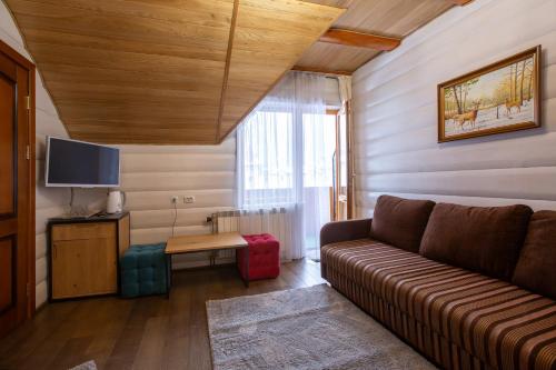 a living room with a couch and a tv at Korona Hotel&SPA in Bukovel