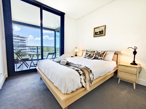 ein Schlafzimmer mit einem großen Bett und einem großen Fenster in der Unterkunft French Country Style in Olympic Park in Sydney