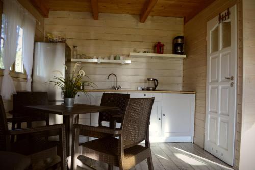 a kitchen with a table and chairs and a refrigerator at Camping Szczecinek Domy Wypoczynkowe in Szczecinek