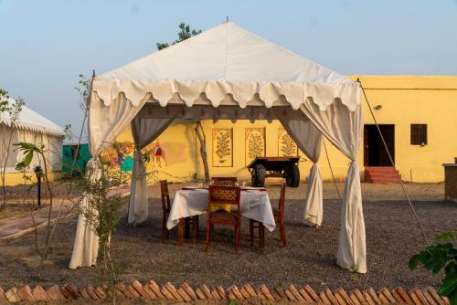 une tente avec une table en face d'un bâtiment dans l'établissement Desert Trails Khuri, à Kūri