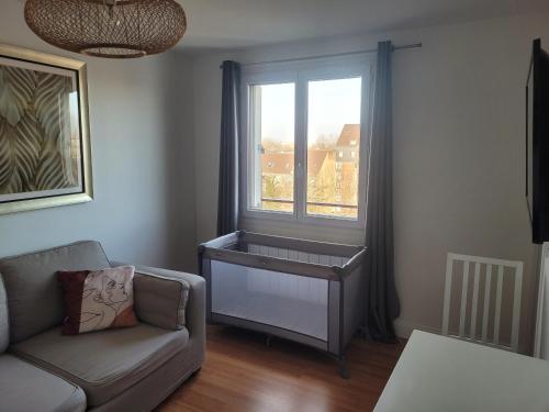 ein Wohnzimmer mit einem Sofa und einem Fenster in der Unterkunft Les jardins du Carrousel - Chambre privée aménagée en T2 in Noisy-le-Grand