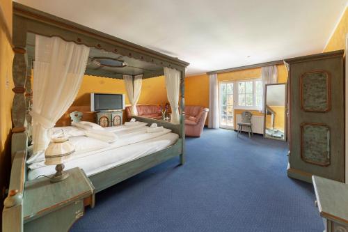 a bedroom with a canopy bed and a living room at Hotel Burger Veniše in Rečica ob Savinji