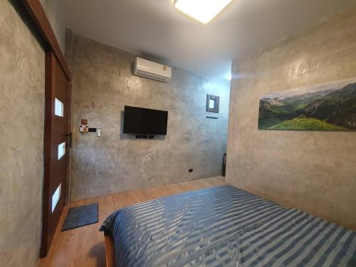 - une chambre avec un lit et une télévision à écran plat dans l'établissement Kedthawa Homestay เฮือนภูผา, à Ban Cho Lae