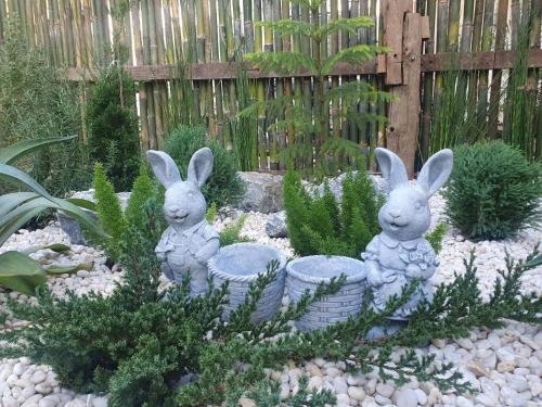 deux statues de lapins dans un jardin dans l'établissement Kedthawa Homestay เฮือนภูผา, à Ban Cho Lae