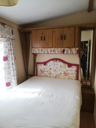 a bedroom with a white bed with a floral headboard at Mobil home Vergnelibert in Chalais