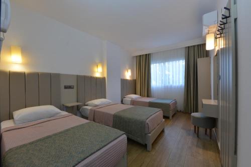 una habitación de hotel con 3 camas en una habitación en Golden Orange Apart, en Marmaris
