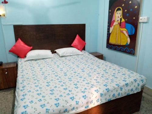 Un dormitorio con una cama con almohadas rojas y una pintura en Blue Cherry Guest House en Calcuta