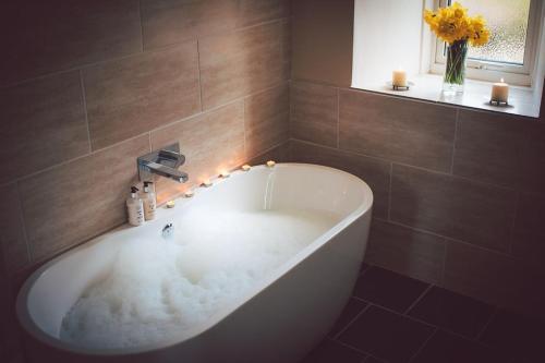 a white bath tub in a bathroom with a window at Press Mains Farm Cottages in Eyemouth