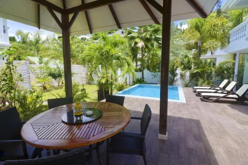 a patio with a table and chairs and a pool at Chateau Elysium - Two bedroom villa 1 in Beau Vallon