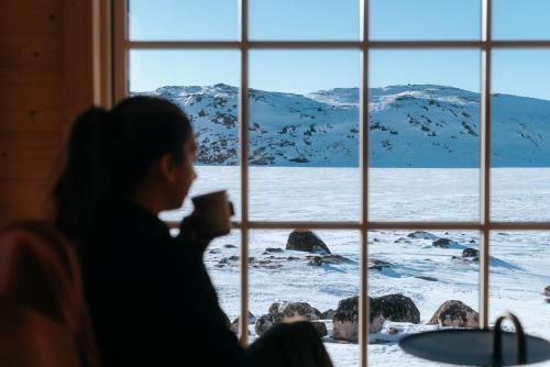 a man looking out a window at a snow covered mountain at Igloo Lodge in Ilulissat