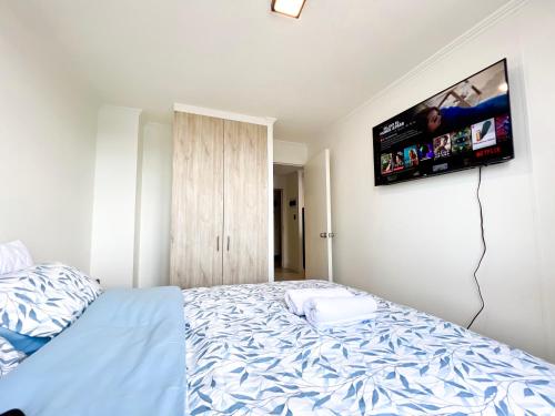 a bedroom with a bed with a tv on the wall at Cómodo departamento con piscina en Los Ángeles in Los Ángeles